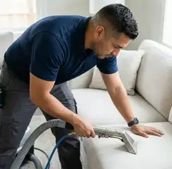 Professional upholstery cleaning technician using an extraction wand to deep-clean a fabric sofa, New Haven, CT.